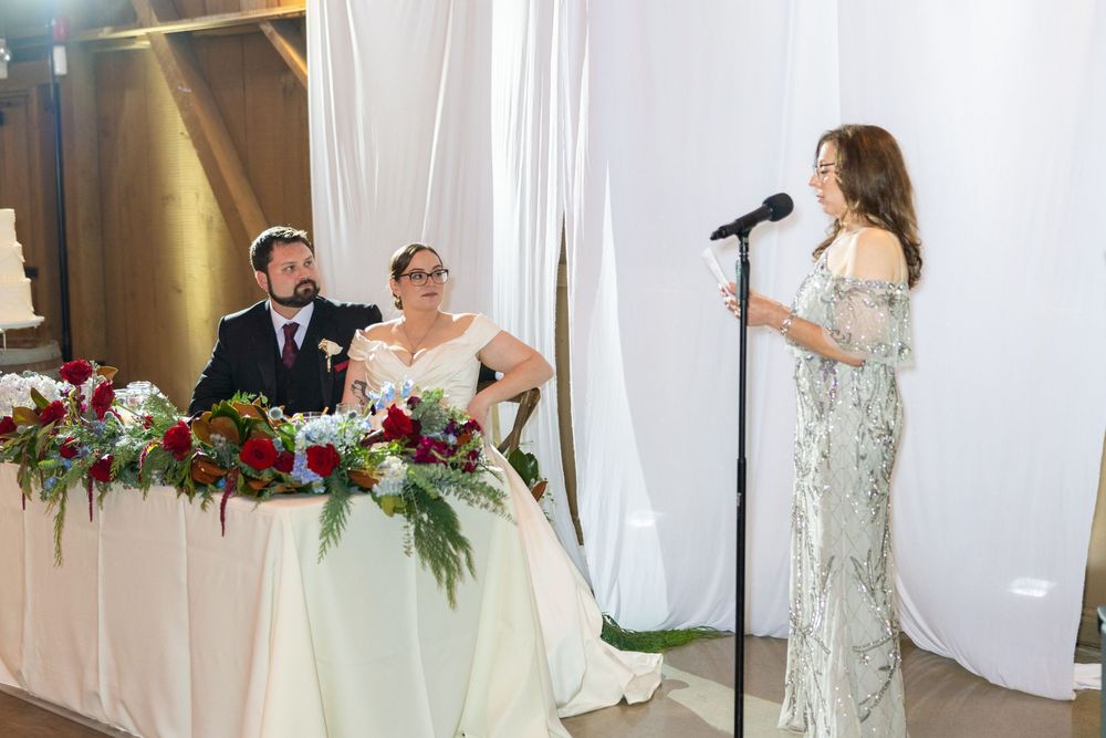 Wedding party members standing in front of white drapes during reception celebration.