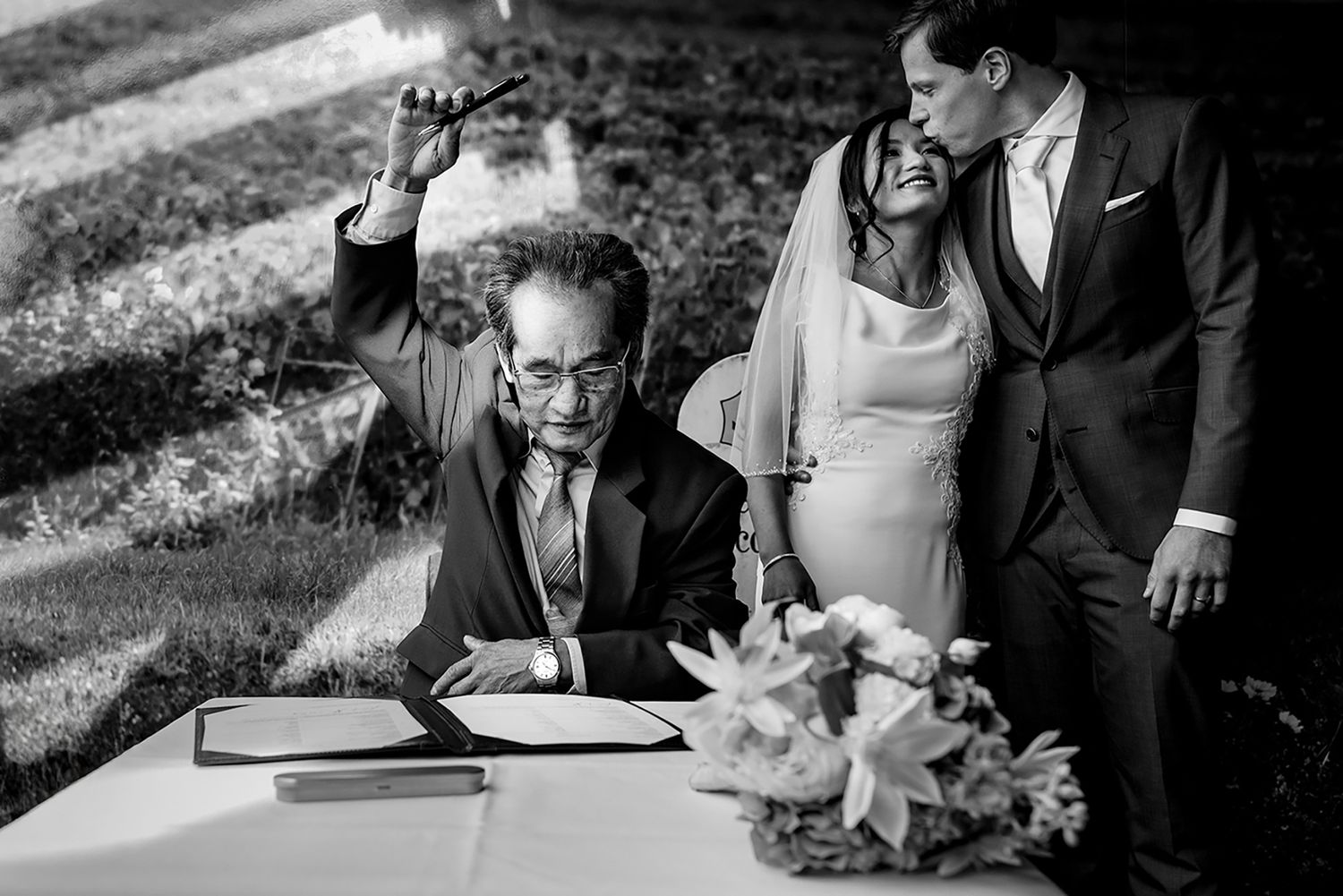 Black and white photo sequence showing close-up shots of people signing documents at a wedding ceremony.