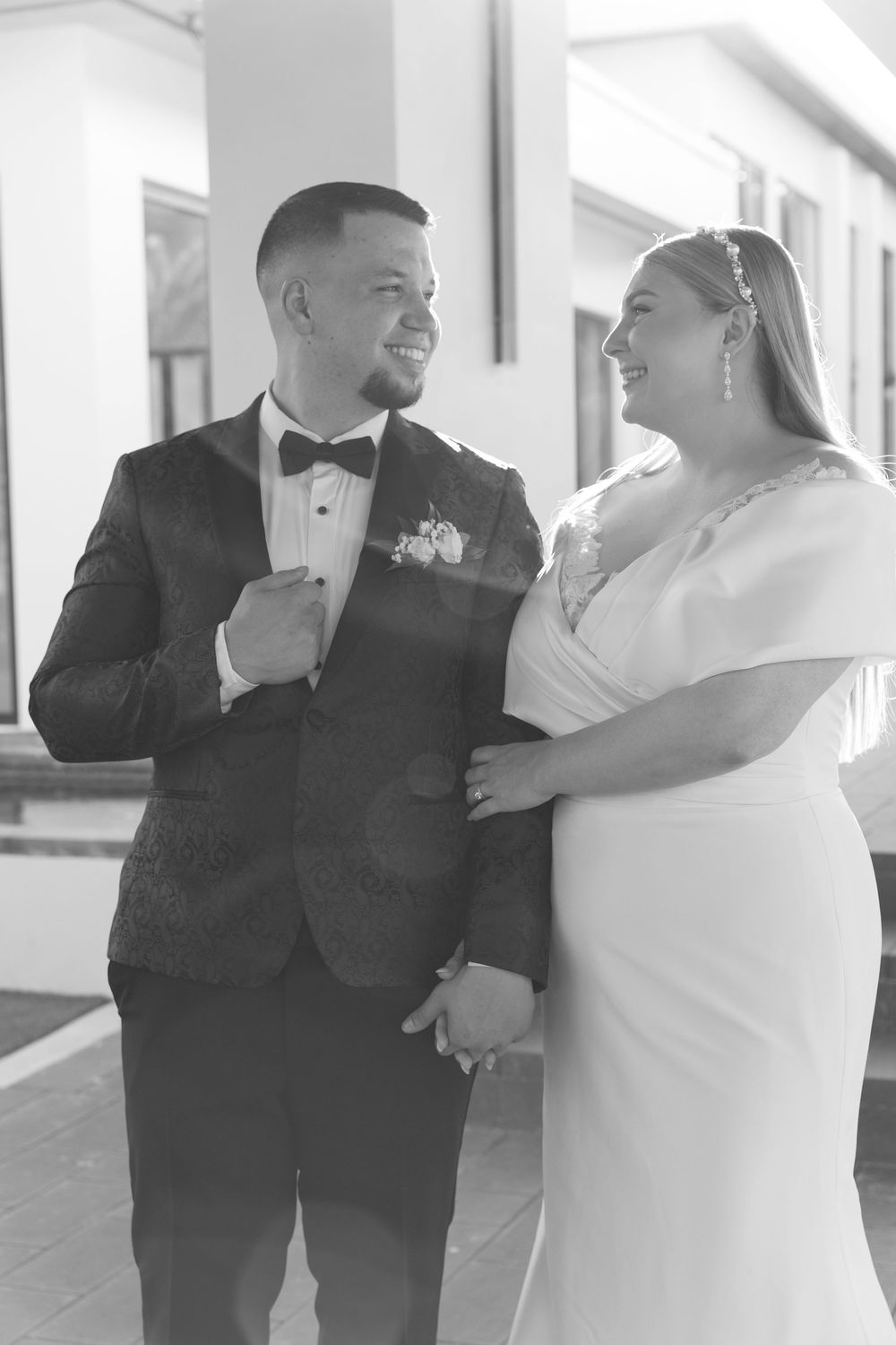 Wedding couple sharing intimate moments in bright white hallway.