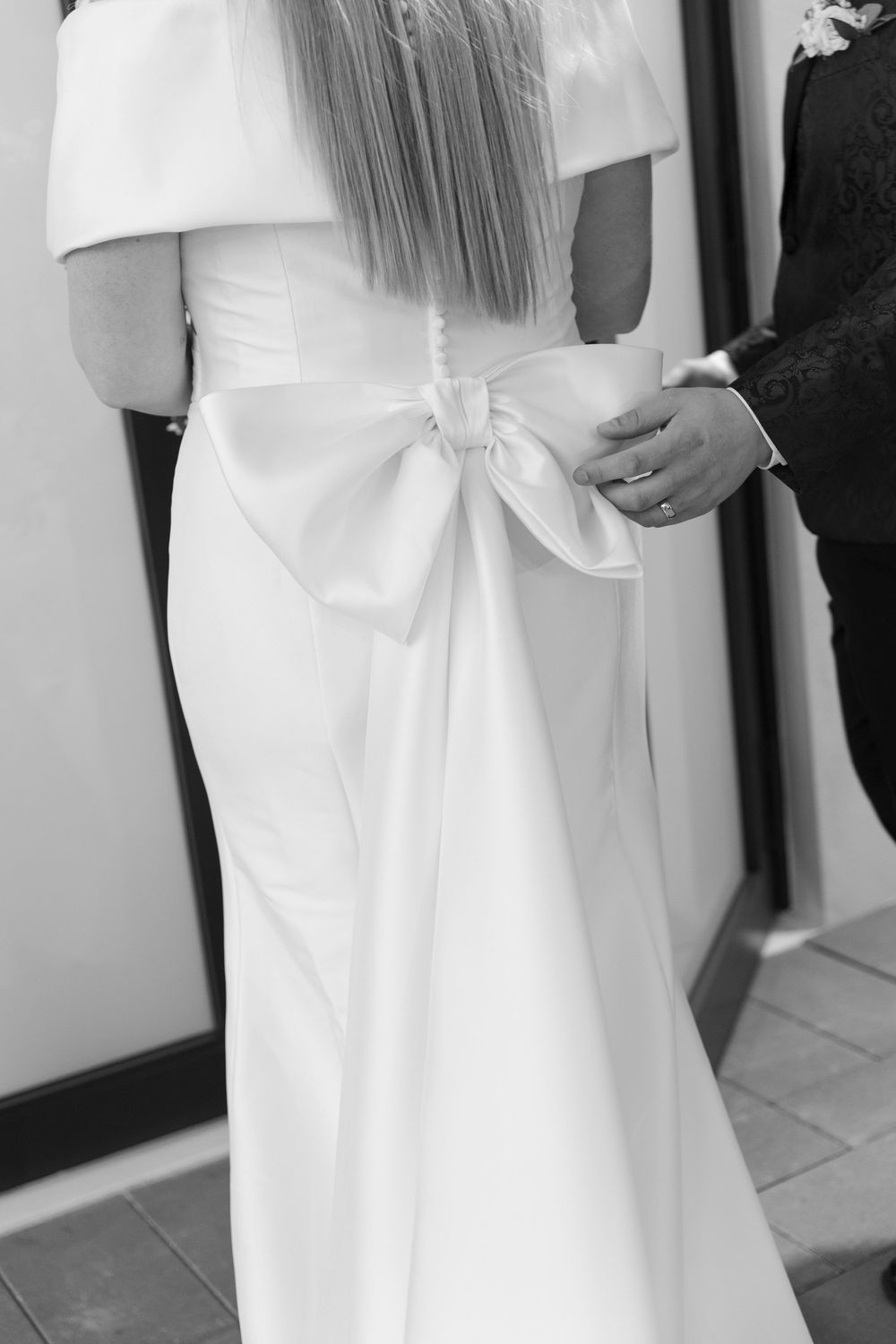 Close-up details of an elegant white wedding dress with a bow accent.