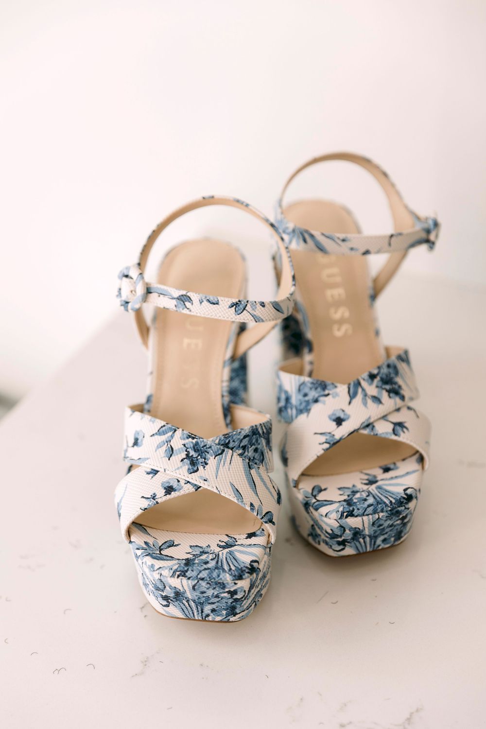 Elegant bridal shoes with blue and white floral pattern displayed on light background.