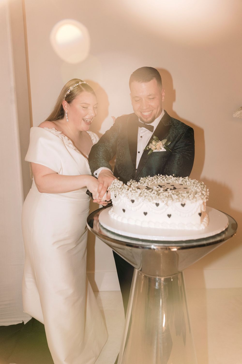 A couple cuts their white wedding cake together during their reception celebration.