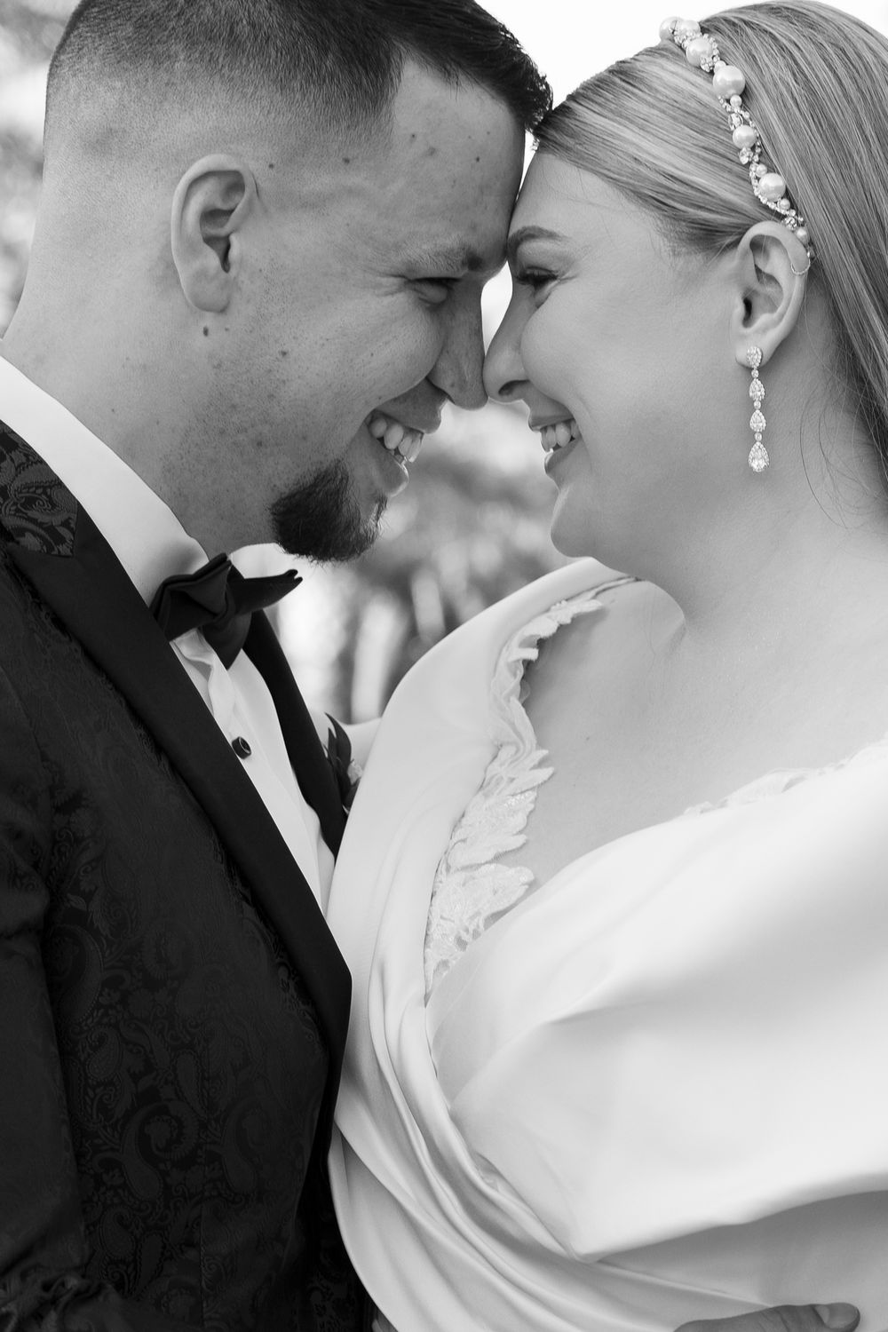 An intimate black and white portrait of a wedding couple sharing a romantic moment.