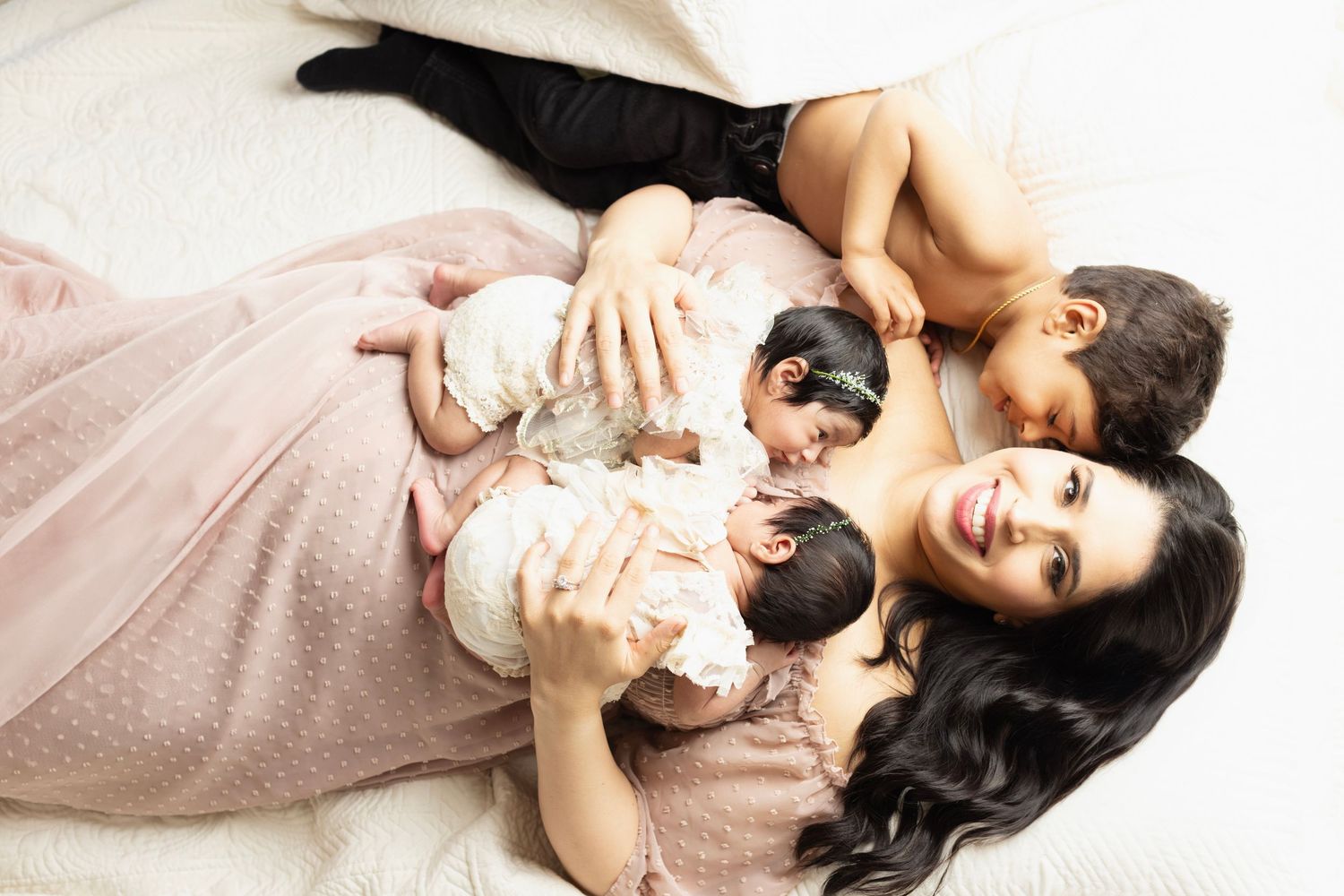 Two small black and white kittens being held and cuddled while laying on light colored fabric.