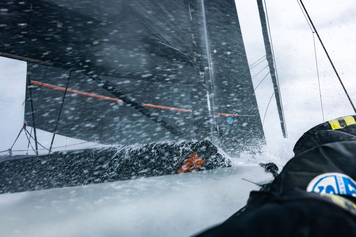 Sailing through rough waters with water splashing over the deck during intense weather conditions.