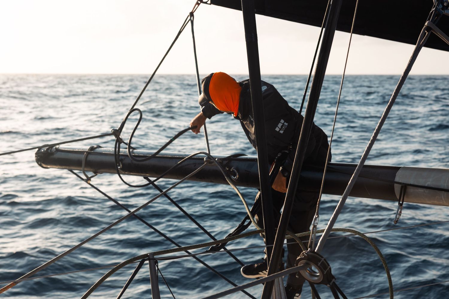Crew members working on deck of racing sailboat in rough seas.