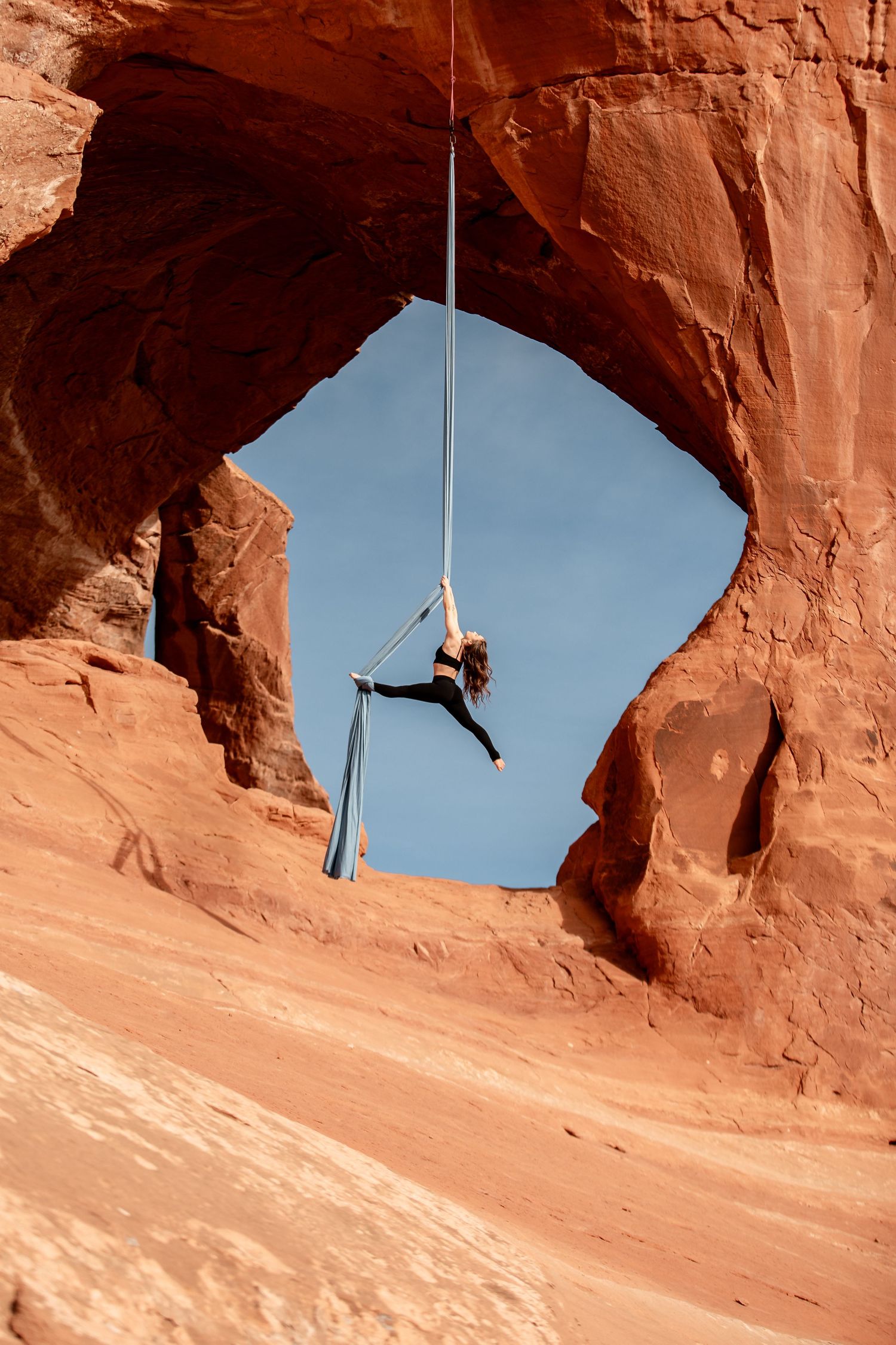 Utah red rock aerial photos, Moab aerial silks photography, aerialist under natural arch, desert, aerial photoshoot, sandstone