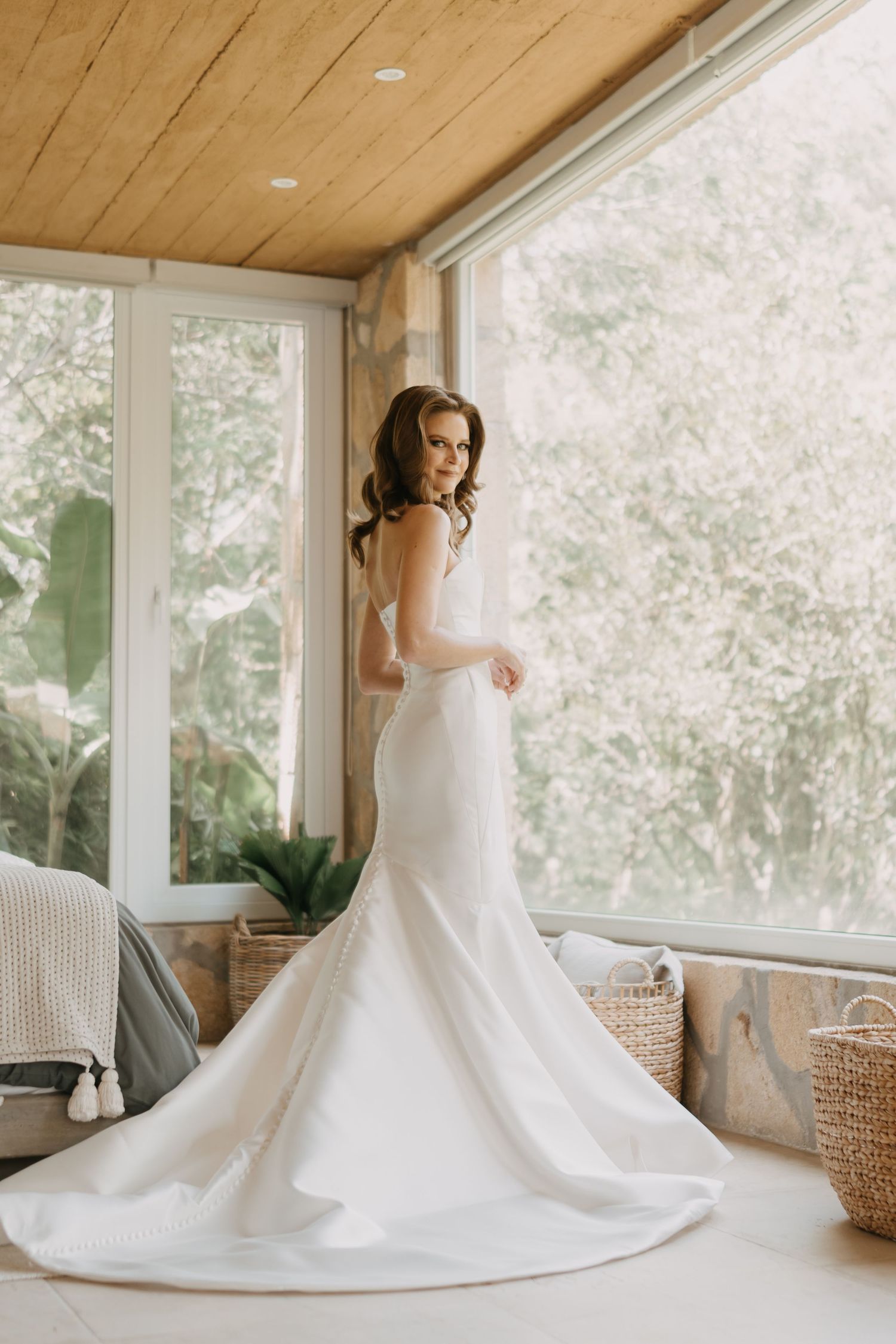 Elegant white wedding dress with dramatic train photographed in sunlit room with wooden ceiling.