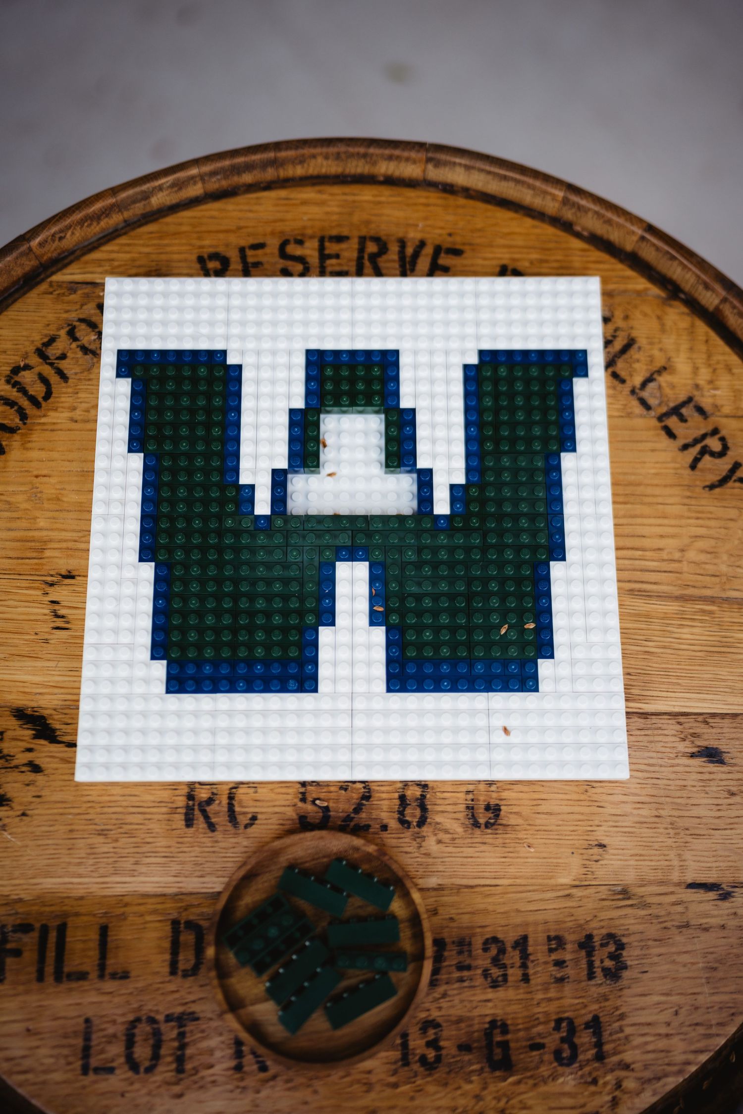 Sequence of wooden wine barrel lids showing a pixelated design pattern in dark green blocks.