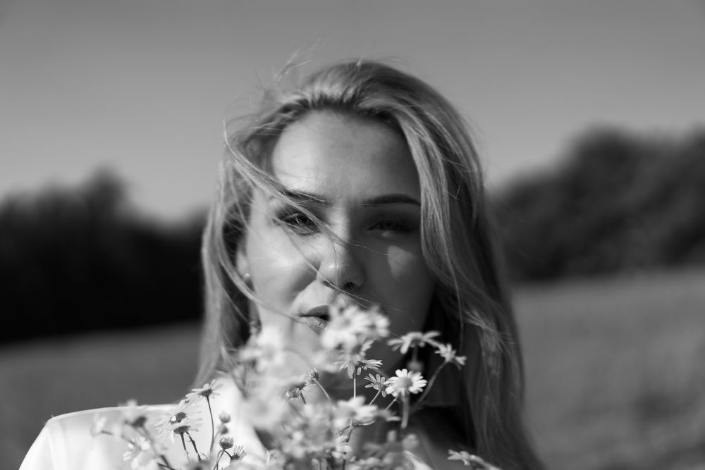 Black and white portrait among delicate wildflowers in a natural outdoor setting.