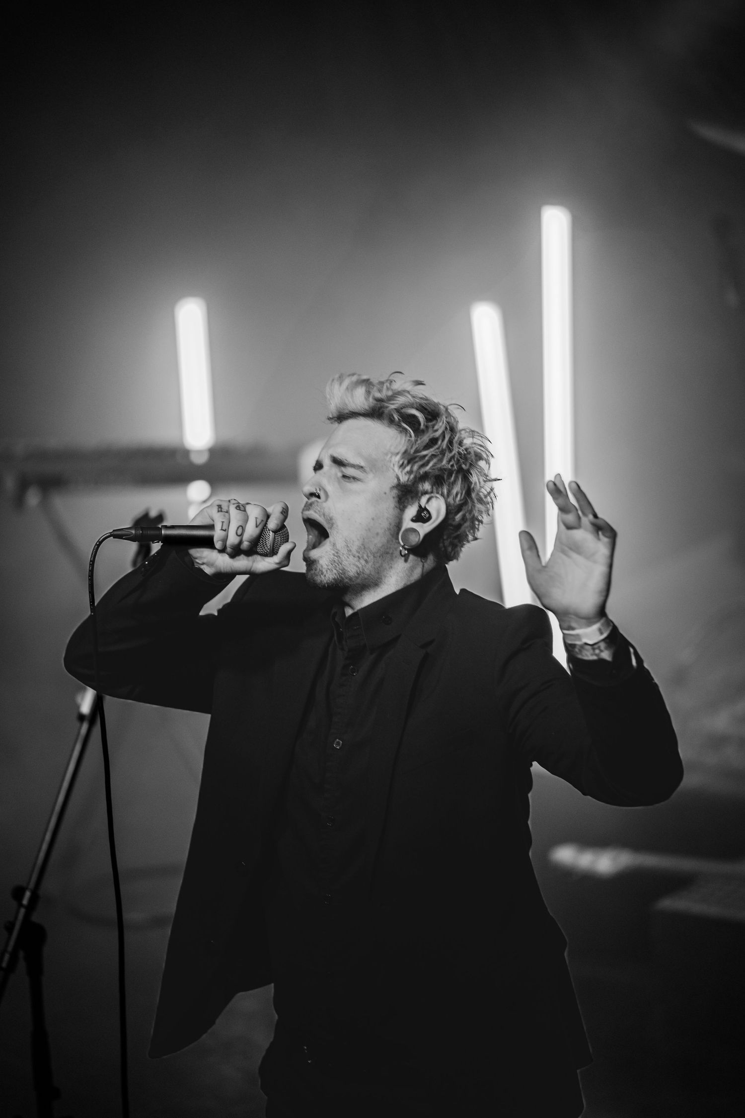 A dramatic black and white photo sequence shows a performer singing passionately on stage with bright lights in the background.