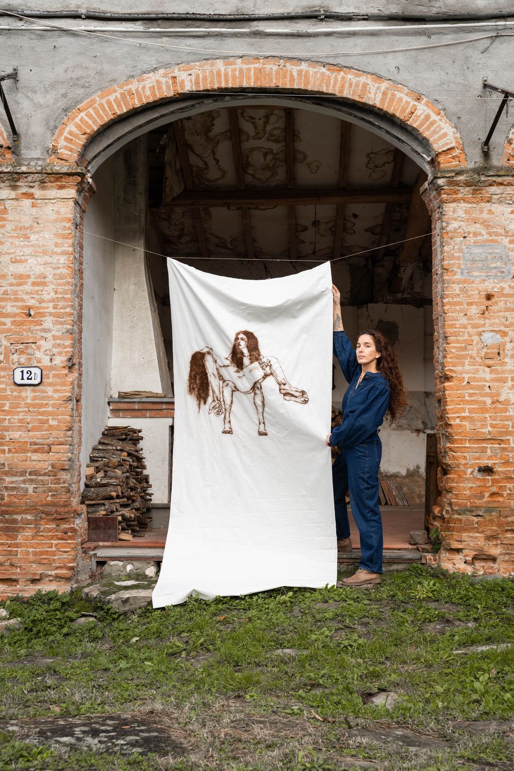 Two people standing in an ancient, arched stone doorway with a white backdrop; location scouting and editorial fashion photography in Tuscan