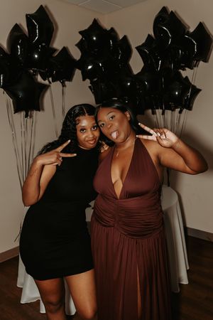 Friends strike fun poses together at a party with black star balloons and wooden flooring.