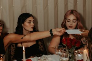 Group enjoying an intimate dinner party with candles and roses on an elegant table setting.