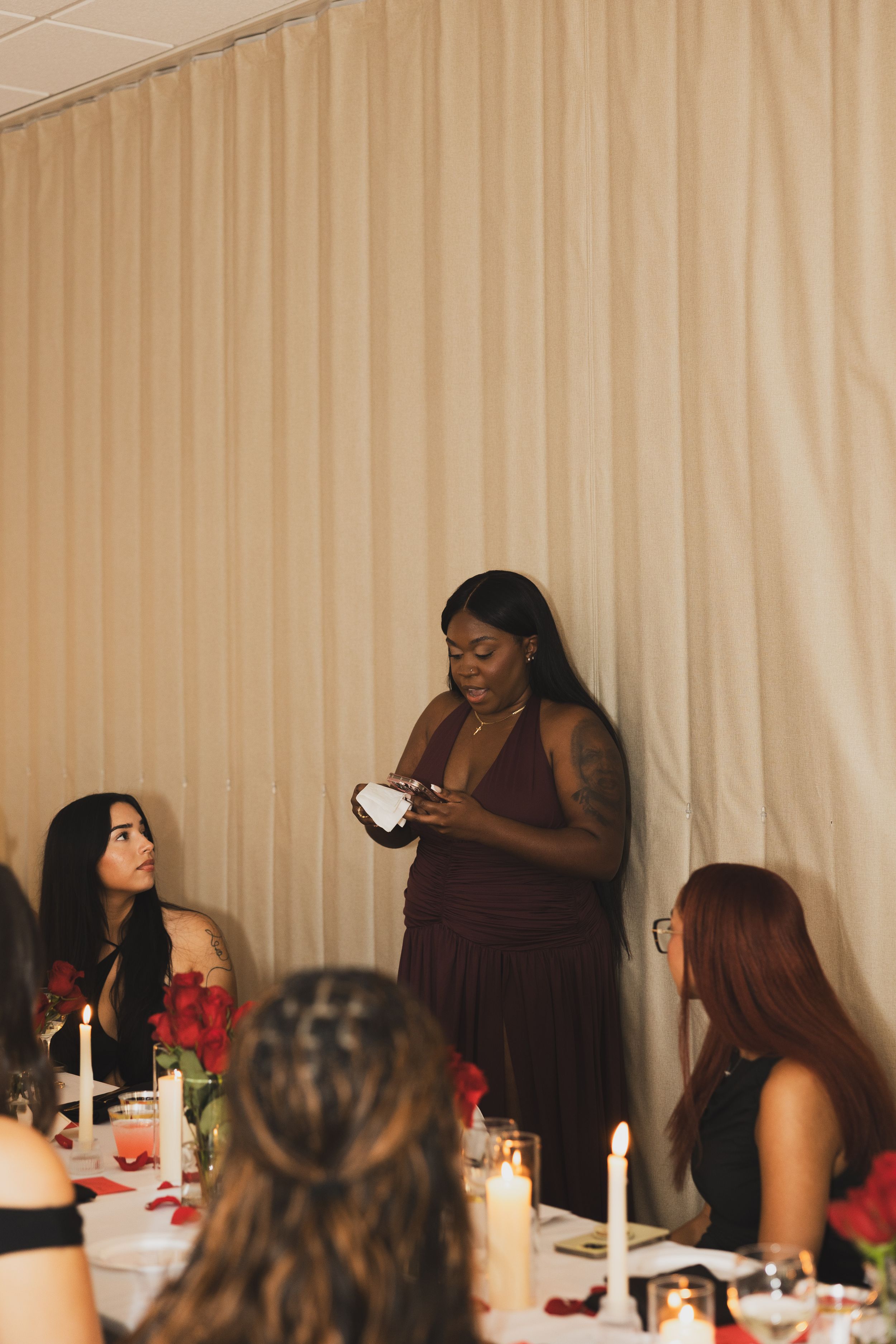 People gathered around a candlelit table enjoying a dinner party with drinks and conversation.