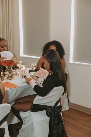 A group celebrates at a dining table with hugs and emotional moments during a special occasion.