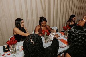 Friends enjoying conversation and drinks at dinner table during evening celebration.