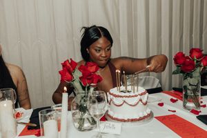 A panoramic view of a formal dining table decorated with red roses and white tablecloths for a special occasion.