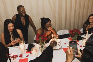 Guests seated at a decorated table with red roses enjoy a festive celebration together.