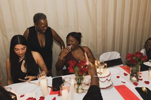 People gathered around a table at a festive celebration with red and white decorations and candles.