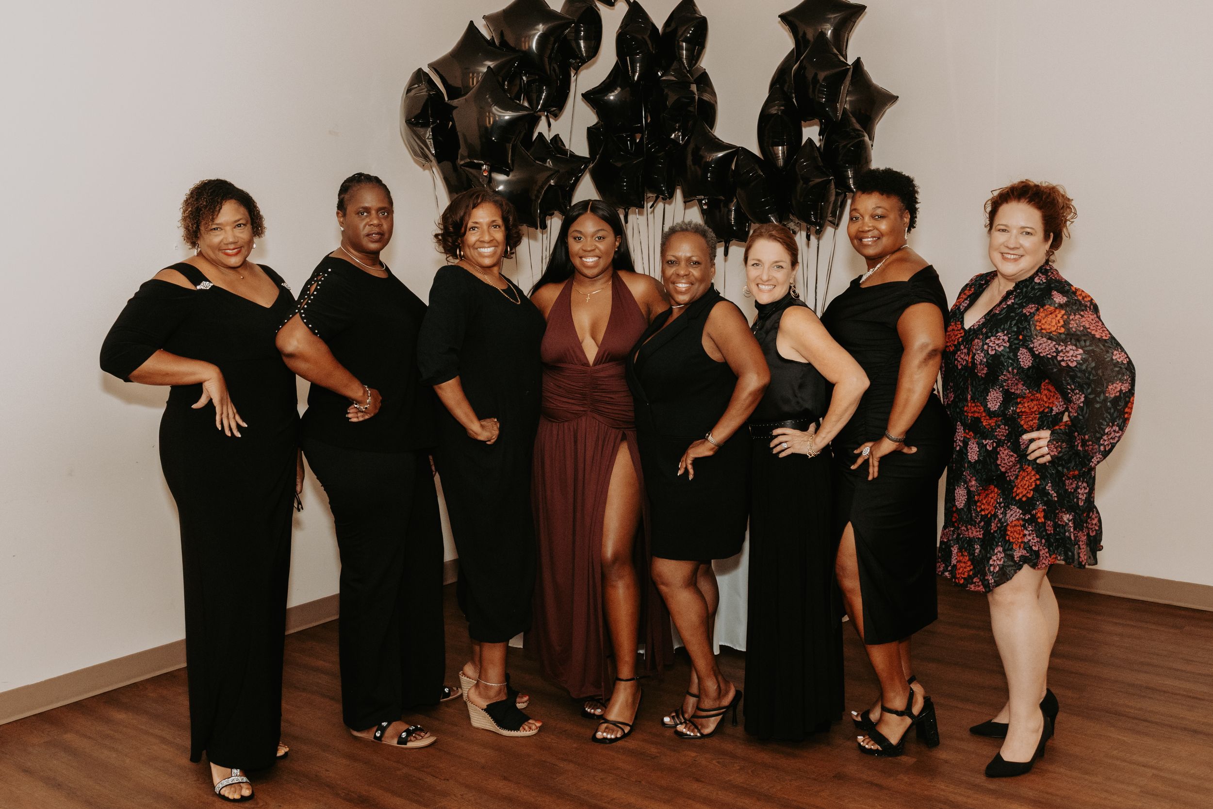 A group photo of party attendees dressed in formal black attire standing together at an event.