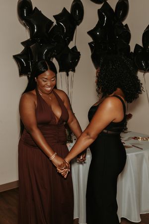 Two people sharing a joyful moment together at an event with black balloons in the background.