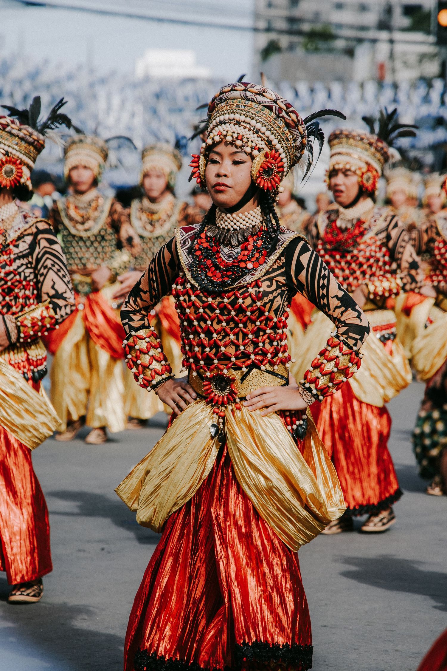 Traditional dancers in gold and red costumes performing in a street festival.