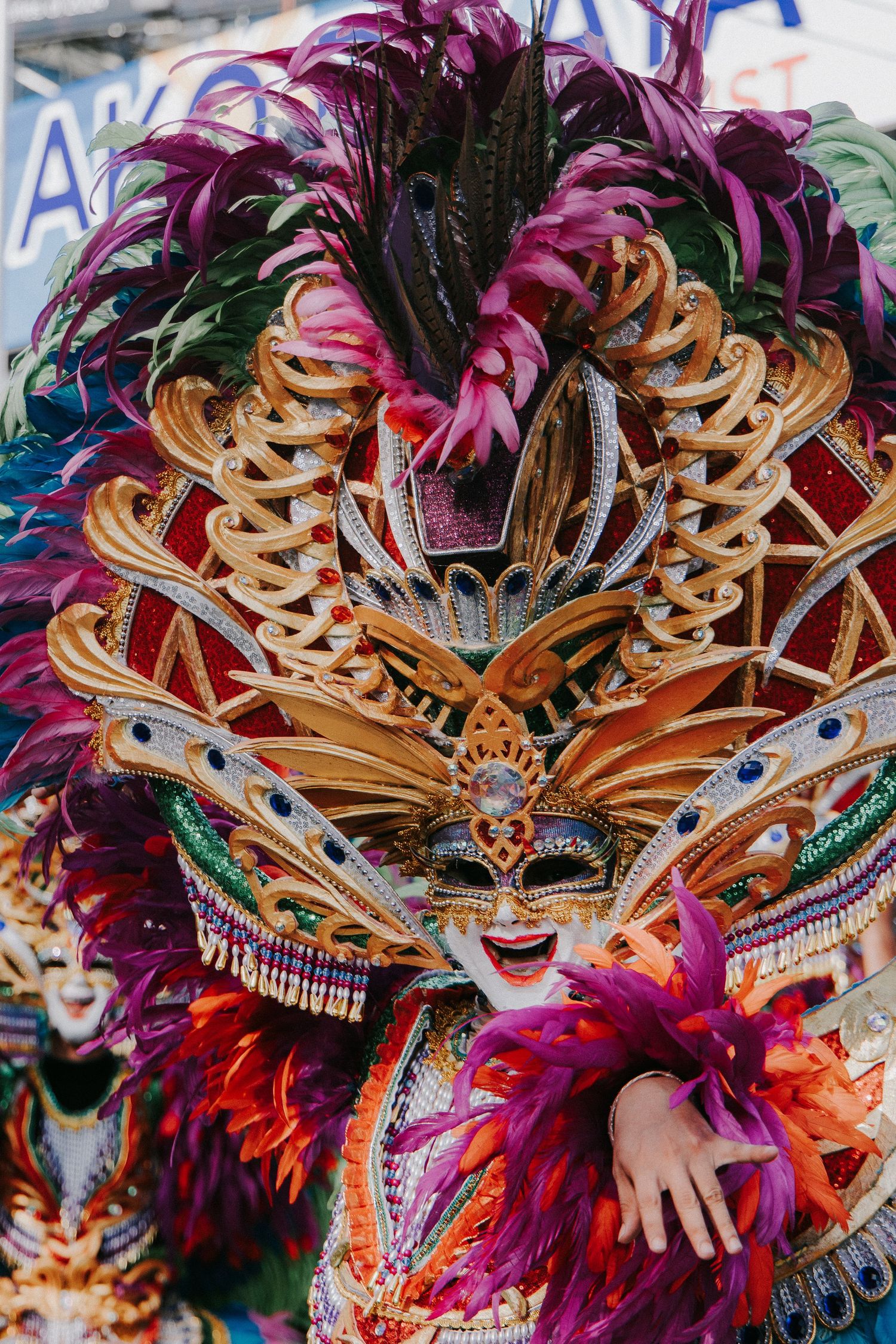 Vibrant carnival mask with elaborate feathers and ornate golden details.