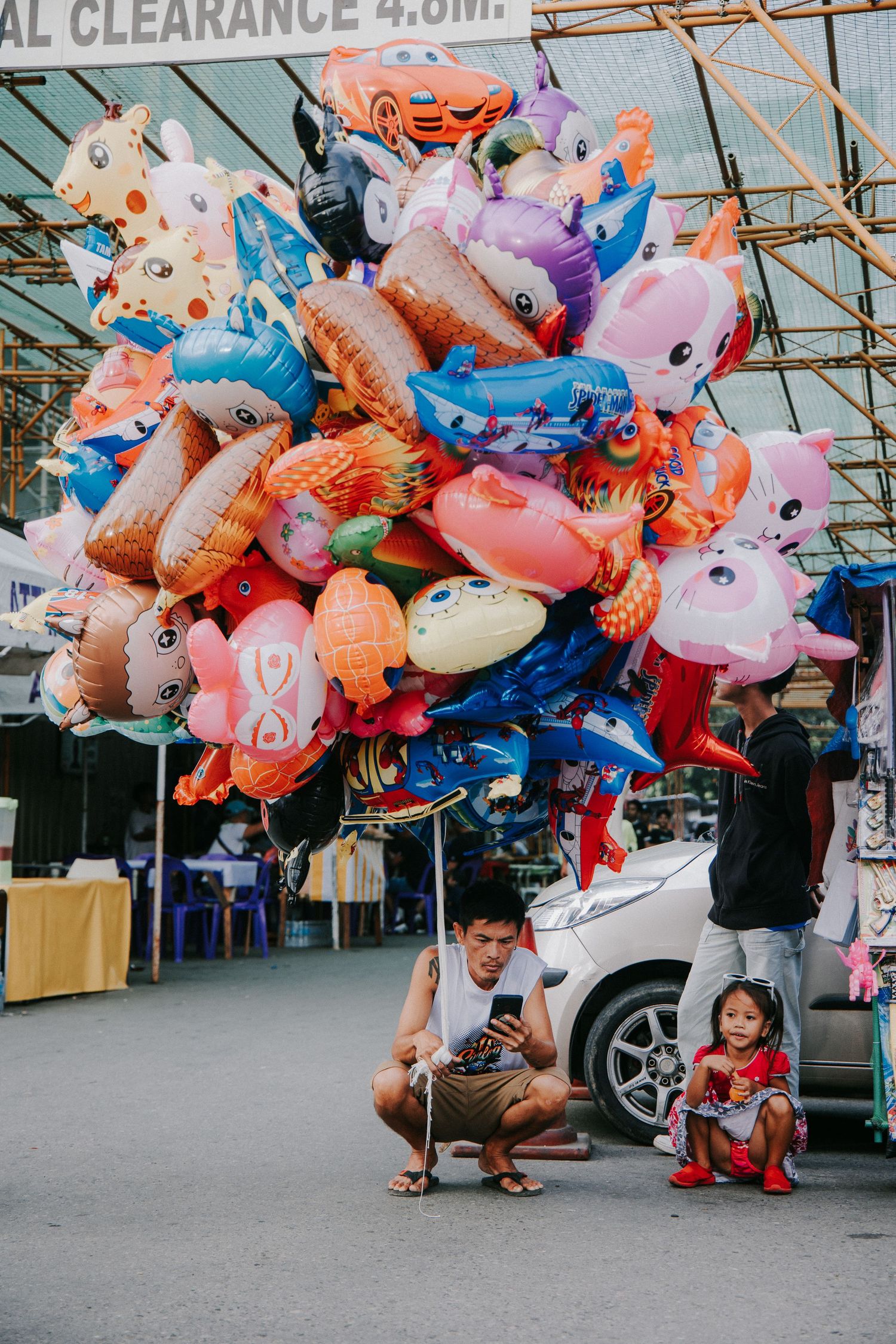 Colorful character balloons being sold by vendors on a street.