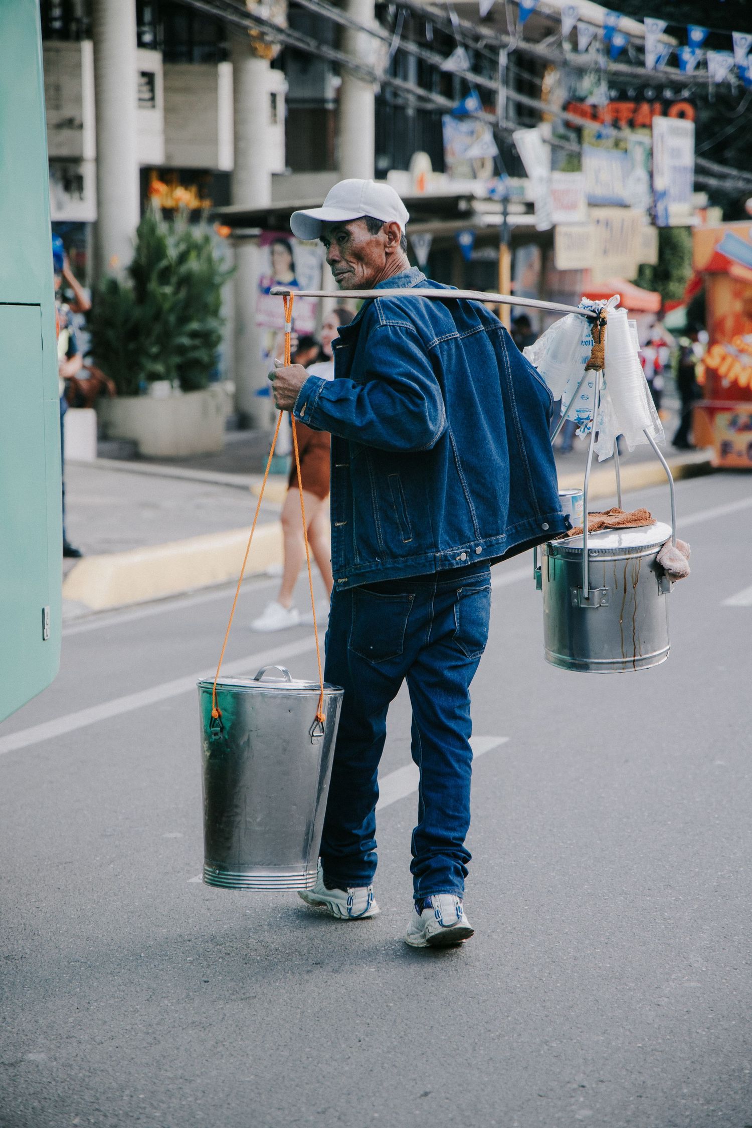 Street cleaners with metal bins walking down an urban road.