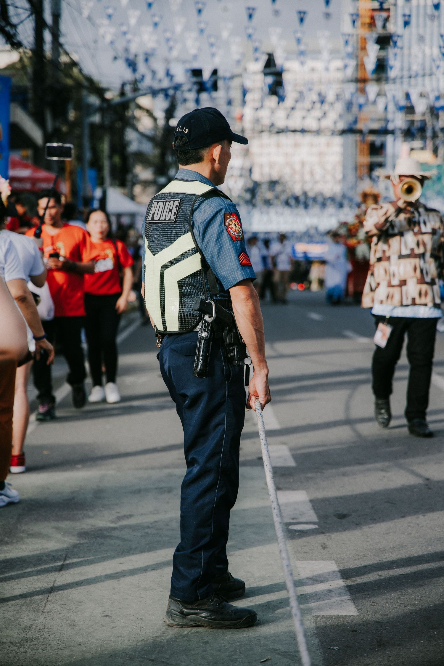 Police officers patrol a festival street with blue banners and decorations overhead.