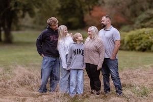 A group of people enjoying a casual outdoor photoshoot in an autumn setting with fallen leaves.