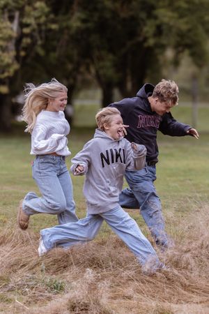 Children run and play together on a grassy hill during an energetic outdoor activity sequence.