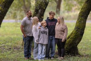 People gathered under moss-covered trees in a natural outdoor setting during a photo session.