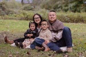 A family sits together on grass during an outdoor autumn photo session.