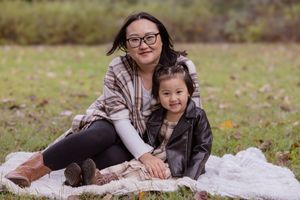 A family relaxes together on a white blanket in an autumn field during an outdoor photo session.