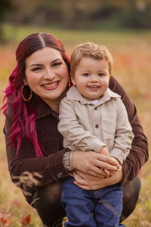 A joyful autumn portrait of parent and child outdoors wearing coordinating brown and beige outfits.