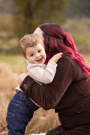 A heartwarming embrace between parent and laughing toddler during an outdoor photo session.