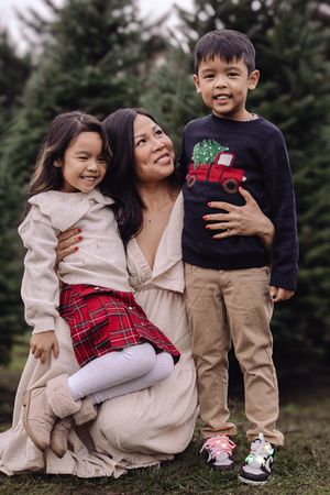 Family portrait session outdoors with evergreen trees in the background showing joyful candid moments together.