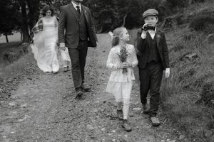 Vintage black and white photograph of people walking along a path in formal attire from the early 1900s.