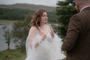 A couple shares joyful moments during their rustic outdoor wedding celebration by a scenic lake.