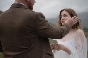 An intimate wedding moment captured against a moody grey sky in the Scottish countryside.