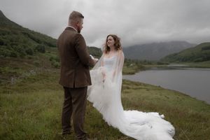 A couple shares an intimate moment during their wedding photoshoot in the misty Scottish Highlands.