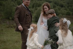 Wedding party laughs together while walking through a green field on an overcast day.