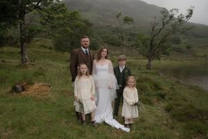 Wedding party poses in scenic mountain landscape with moody overcast skies and rustic natural backdrop.