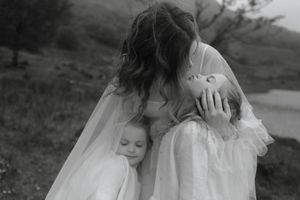 A bride plays with her veil while posing in a white wedding dress outdoors during a photo session.