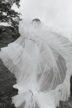 A series of black and white photographs showing delicate layers of white tulle fabric flowing in an ethereal pattern.