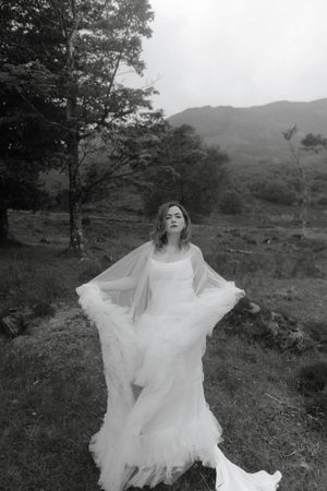 A dreamy black and white photograph of a flowing white wedding dress in a misty mountain landscape.