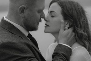 Intimate black and white portrait of a romantic couple in formal attire sharing a tender moment.