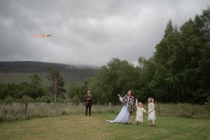 Panoramic view of a misty landscape with trees and figures in white dresses scattered across a green field.